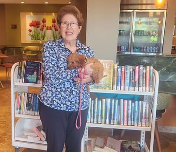 An RHPL Lobby stop patron stands in front of carts of books, holding a small dog.