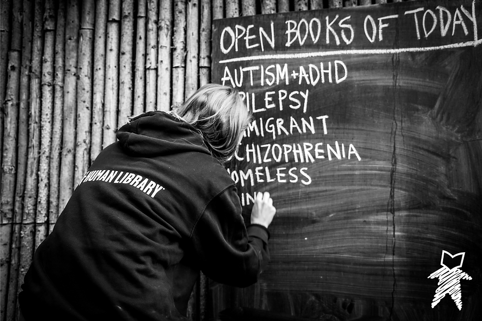 A person writing on a blackboard. Under the heading "Open Books of Today" the person writes titles including: Autism+ADHD, Epilepsy, Immigrant, Schizophrenia, Homeless