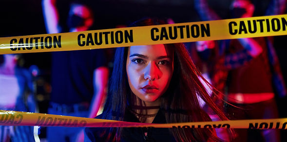 A woman stands behind a caution tape.