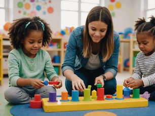 Two children sit on the floor with a teacher and stack colorful toy blocks