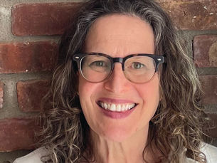 An image of author Catherine Newman. A smiling woman in glasses with curly brown and gray shoulder-length hair.
