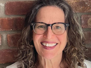 An image of author Catherine Newman. A smiling woman in glasses with curly brown and gray shoulder-length hair.