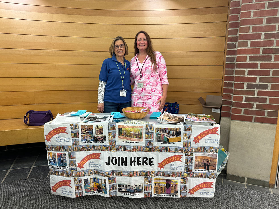 Two Friends members stand behind a table with a "Join Here" sign