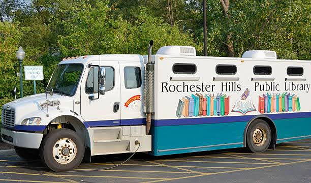 A photo of the original RHPL bookmobile, a modified truck with "Rochester Hills Public Library" and images of books on the side.