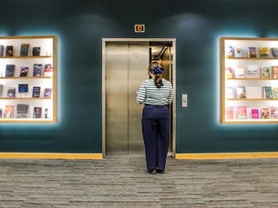 A woman stands outside of an elevator waiting to enter