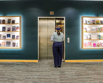 A woman stands outside of an elevator waiting to enter