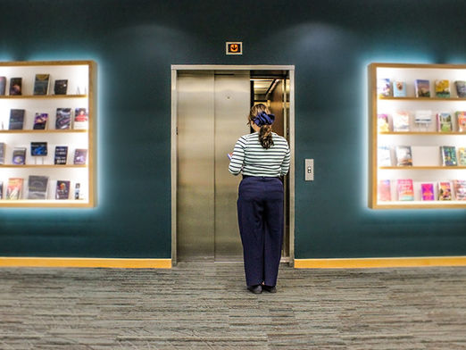 A woman stands outside of an elevator waiting to enter