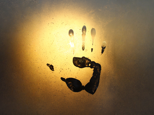 A photo of a handprint left in condensation on a piece of glass.