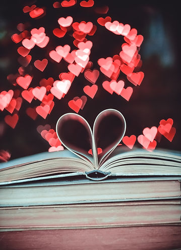 An open book with the page in the shape of a heart, with red and pink overlapping hearts in the background
