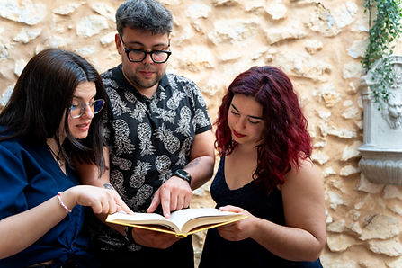 Three adults reading and discussing a book together