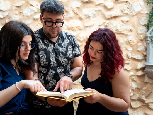 Three adults reading and discussing a book together