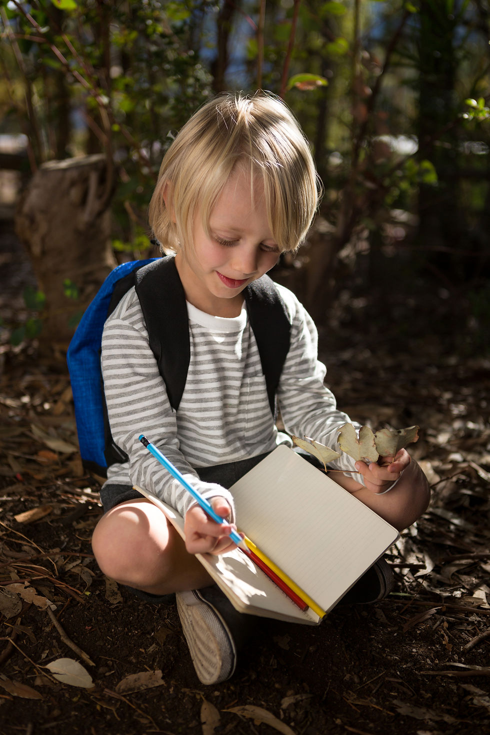 A child sits outside and writes in a journal