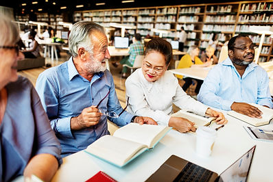 A group of adults with open books, smiling and talking with each other.