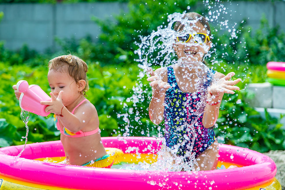 A toddler and school-aged kid splash and play in an kiddie pool