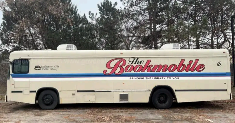 A photo of the RHPL bookmobile from 2018-2022. A modified bus, "The Bookmobile" is written on the side along with "Bringing the Library to you"