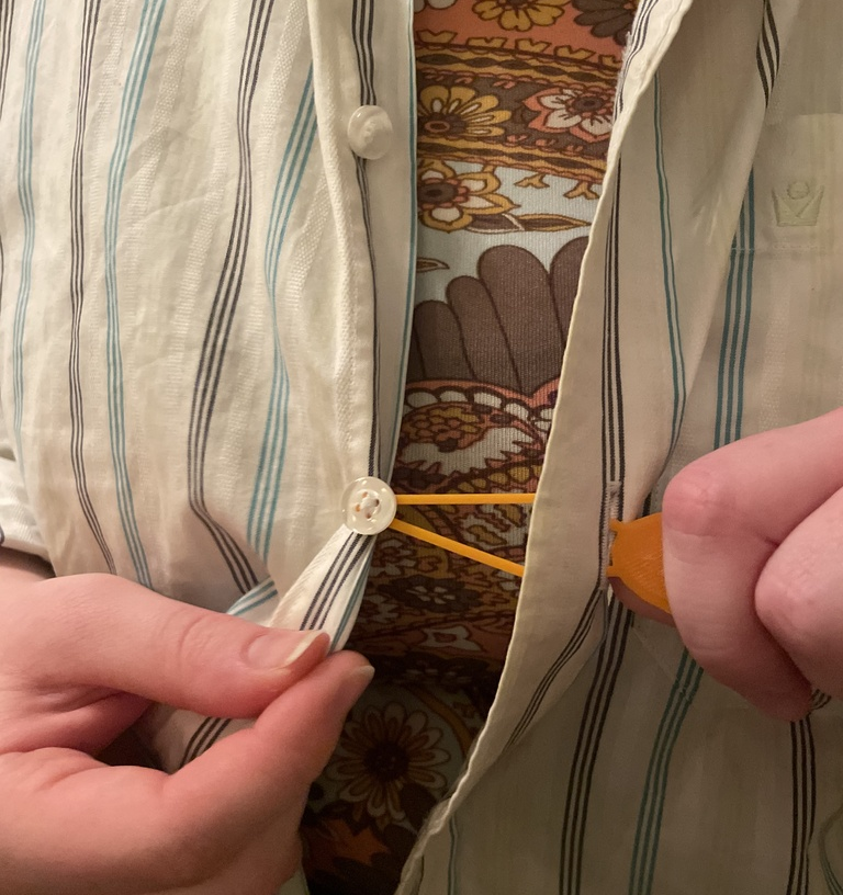 A 3D printed device that can loop around a button and helps pull it through a hole.