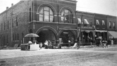 A black and white photograph with old buildings and a horse and buggie 300 Block on the East Side of Main Street