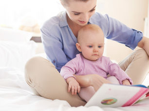 A young woman and her infant sit reading a book together