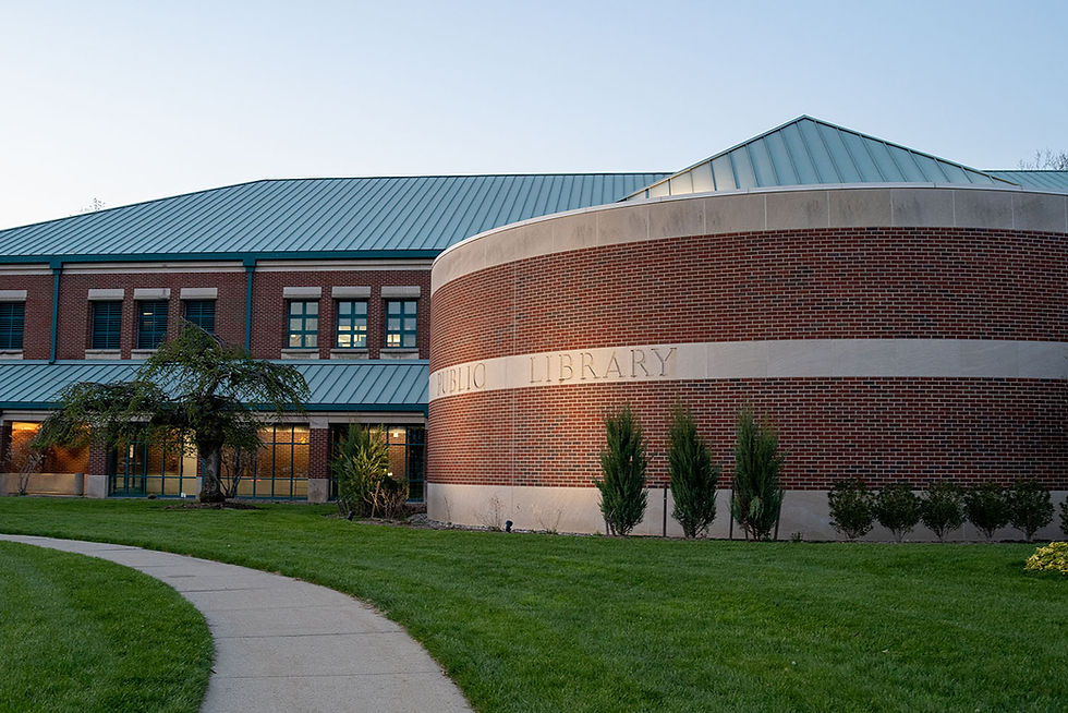 The rounded front side of RHPL at night. Lights shine on the words "Public Library"