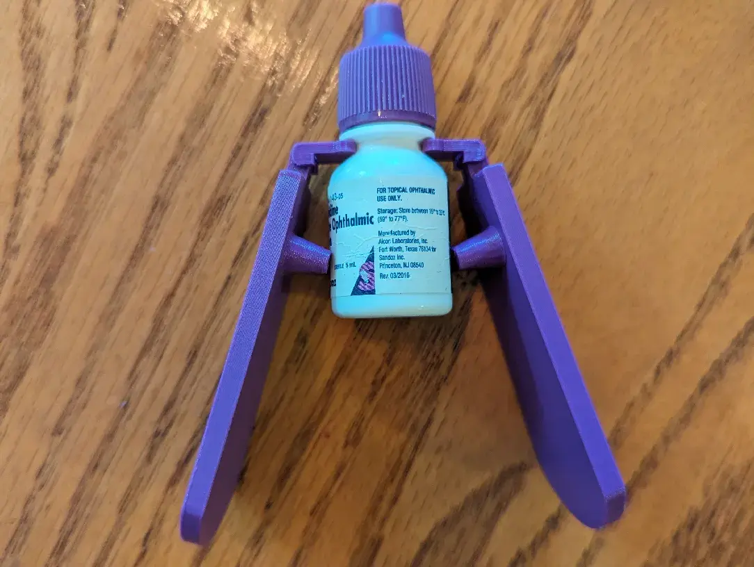 Two 3D printed clips hold a standard prescription eye drop container making it easier to administer