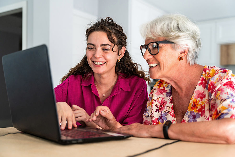 A teenager helping an elderly woman use a laptop