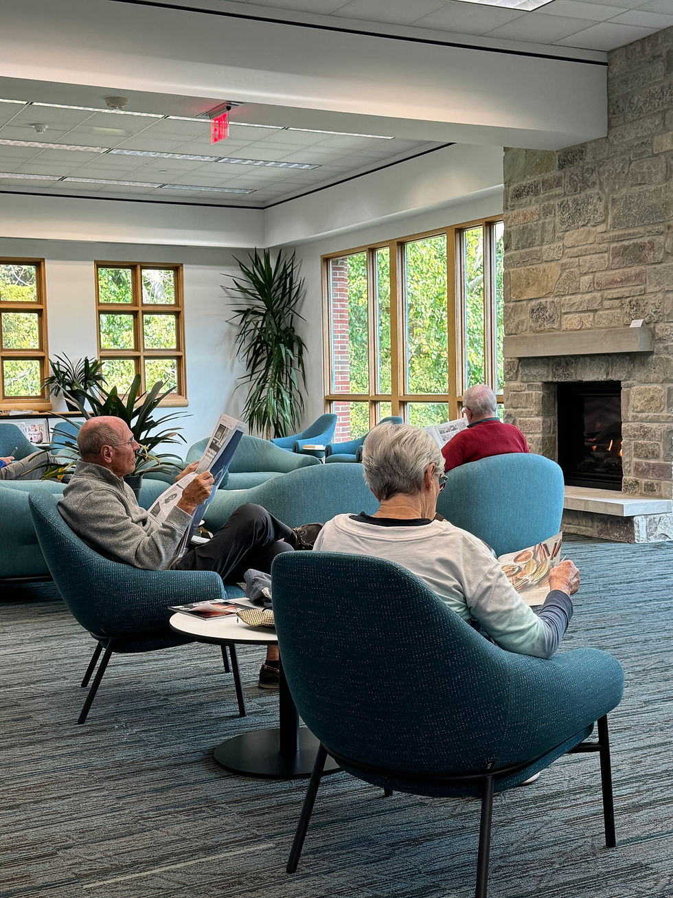 A man and women read magazines and newspapers near the fireplace